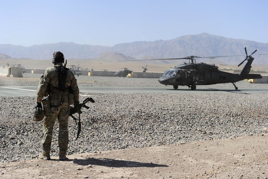 a soldier standing outdoors waiting for a helicopter