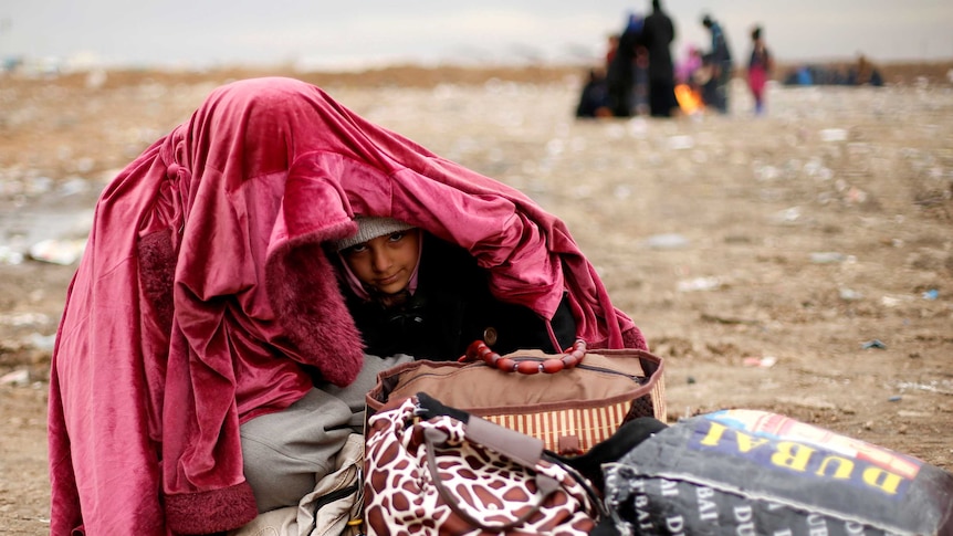 A displaced woman covers her daughter after fleeing the battle near Mosul.