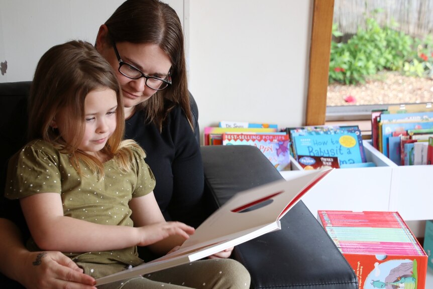 A young mother reads to her young child on a couch