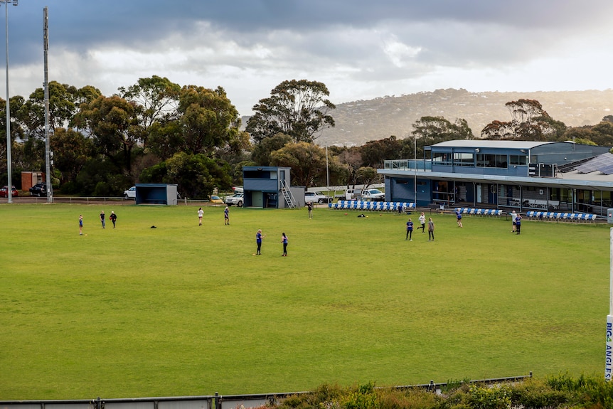 Green football oval with women running in front of granstand