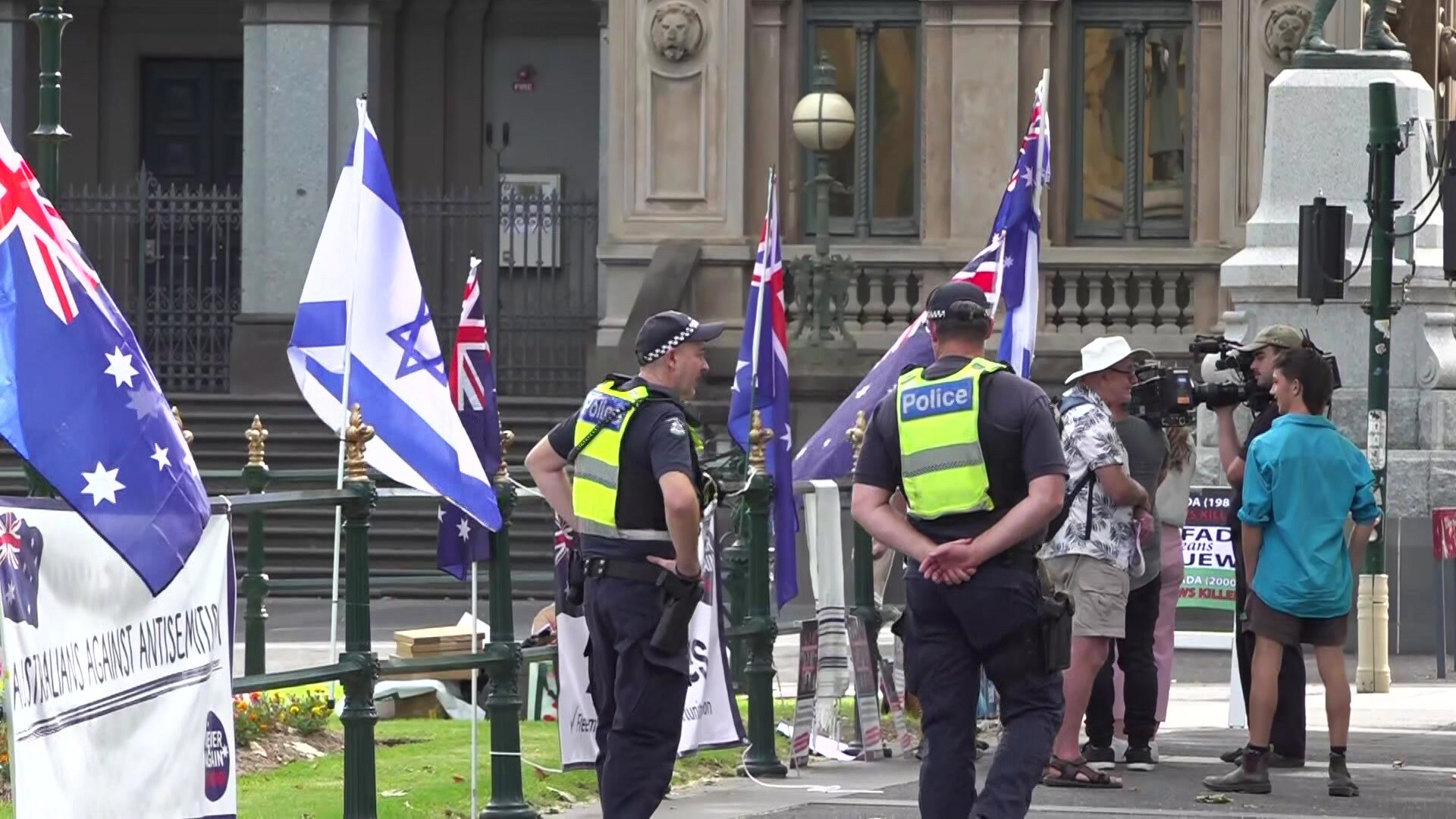 People congregate with Australian and Israel flags, with police officers also present.