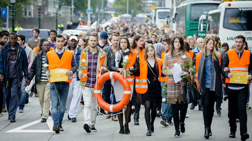 Protesters march during a silent rally in support of migrants and refugees in The Hagu