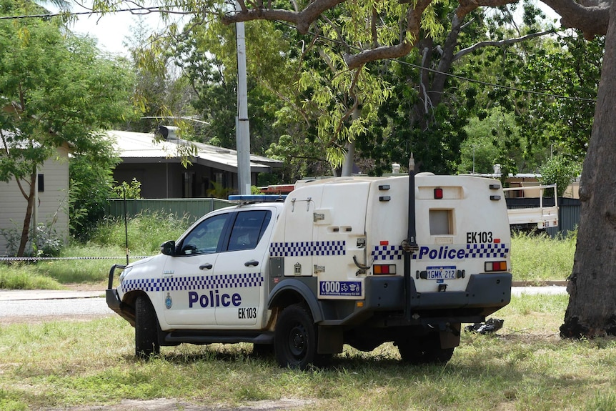 A white and blue police van parked on grass in front of a house.