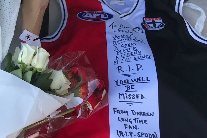 Bouquets of flowers and a signed St Kilda vest lie outside the St Kilda Football Club headquarters.