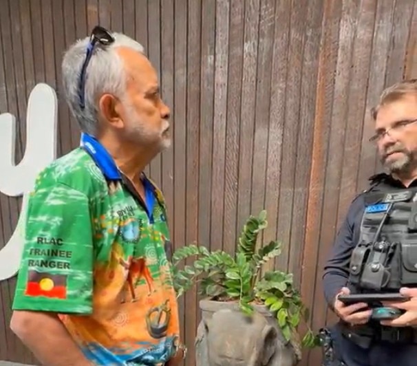 Two men face each other, one wearing a police uniform.