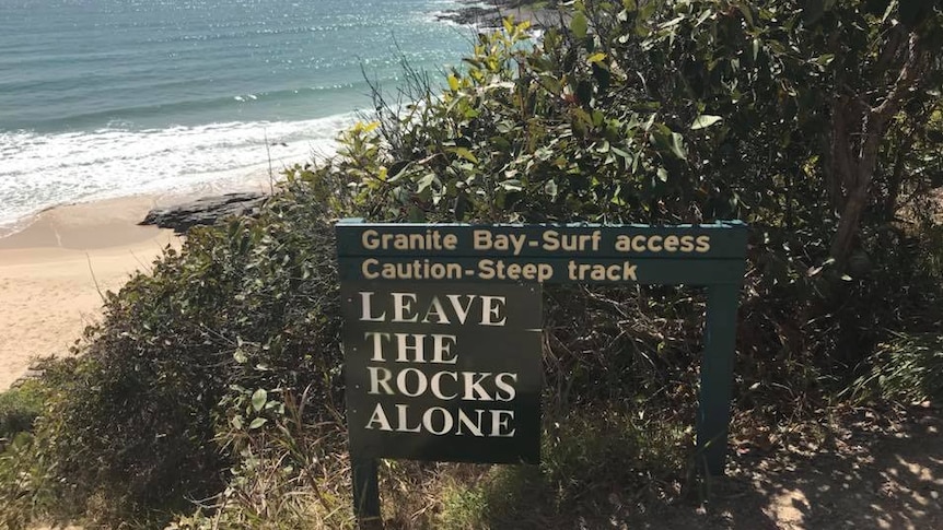 A sign post at the entrance to a beach