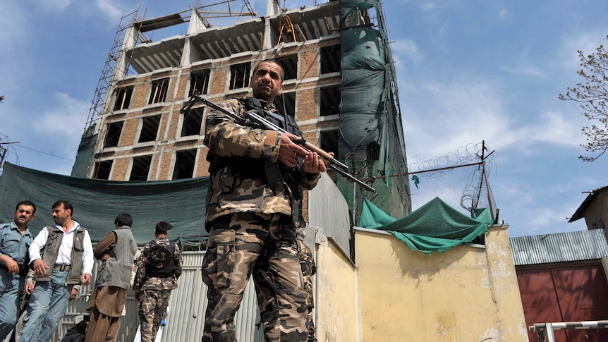 Afghan policeman stands guard outside building