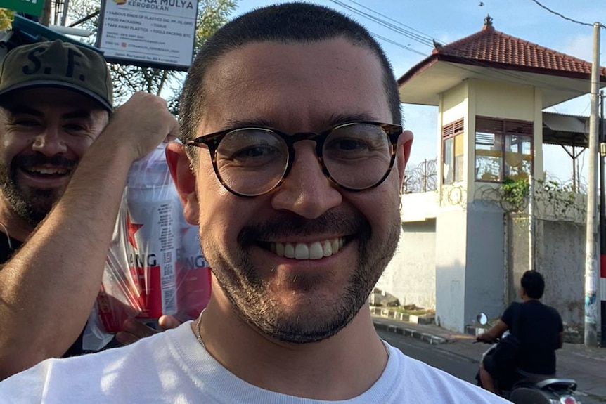 un homme souriant de près portant des lunettes