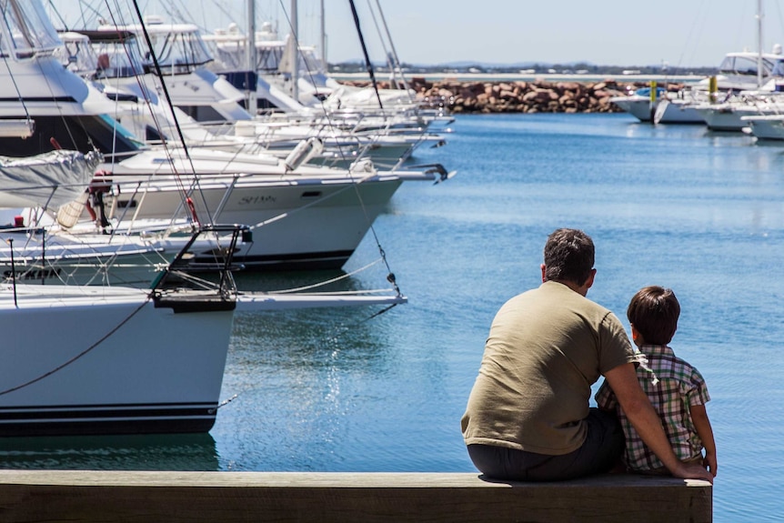 A man and boy sit on a pier.