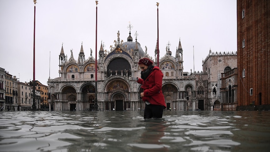 A woman crossing flood waters in Venice.