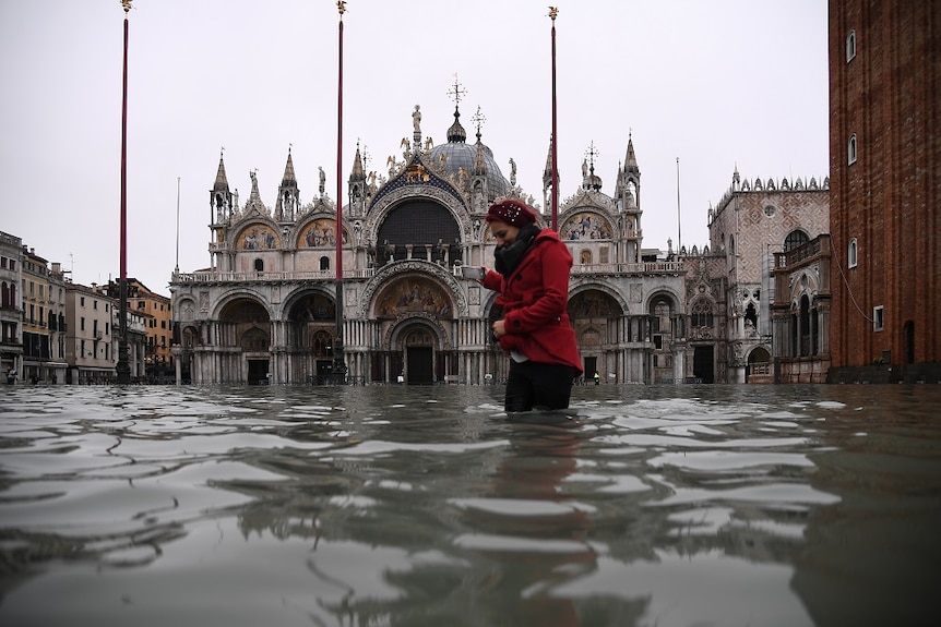A woman crossing flood waters in Venice.