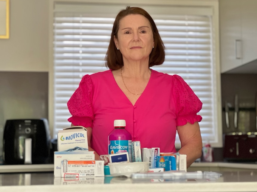 A brunette woman with medication standing in a kitchen