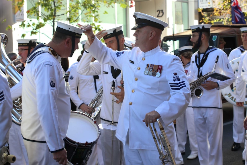 A Navy officer adjusts the hat of a fellow sailor ahead of the Anzac march.