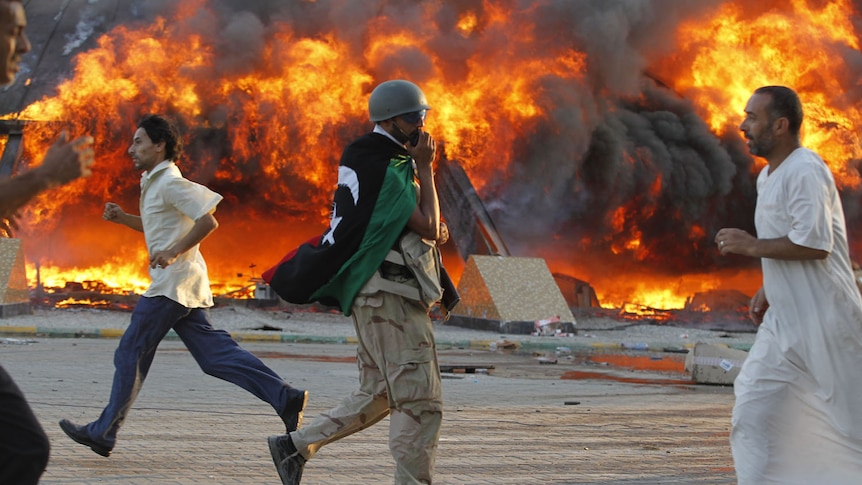 Libyan rebel on walkie-talkie near tent fire