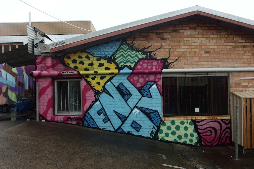 A brick wall, half of which is painted in bright colours.