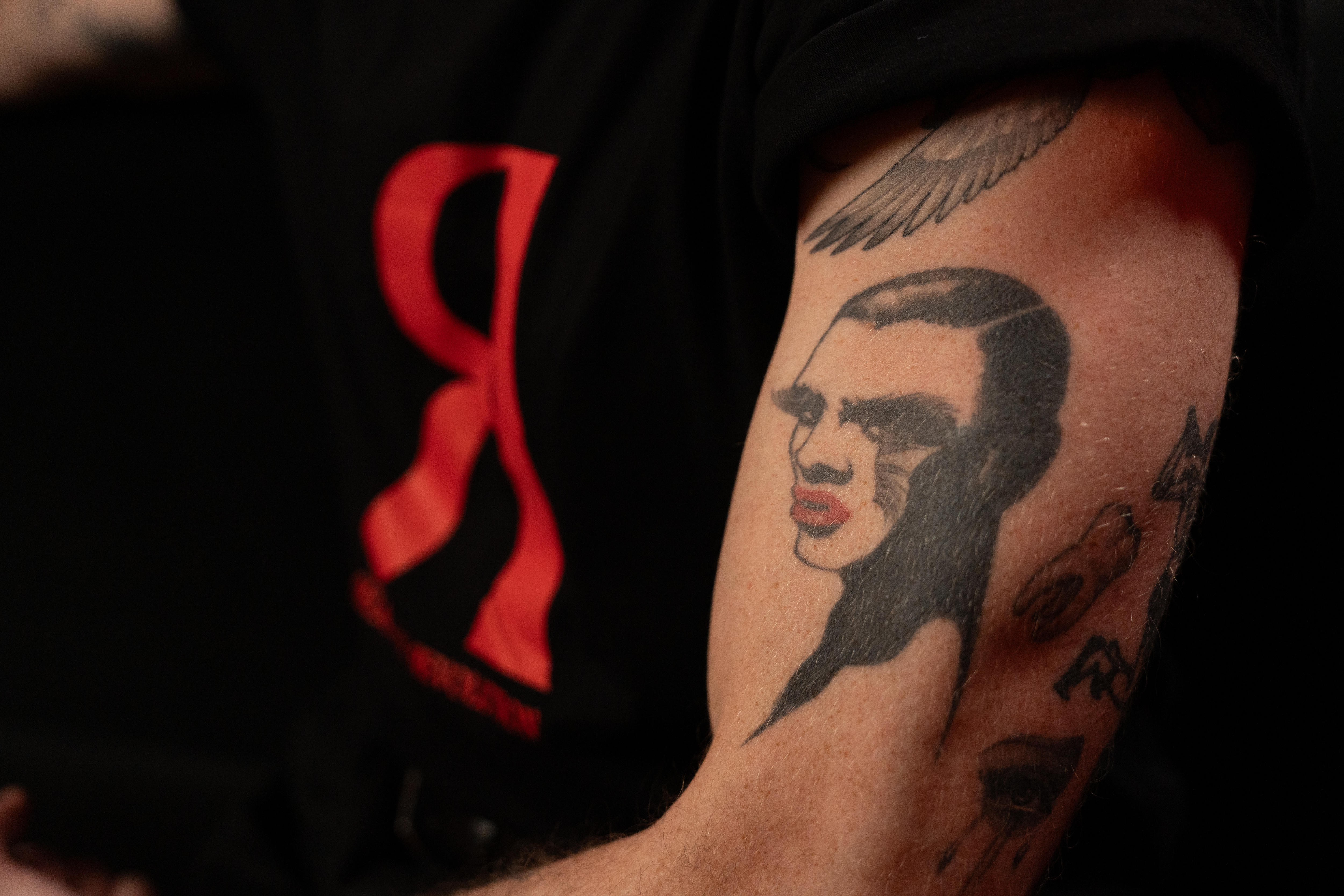 A close-up on the tattoos on the strong arm of Reuben Kaye, 41, including a caricature of a man in lipstick and fake eyelashes.