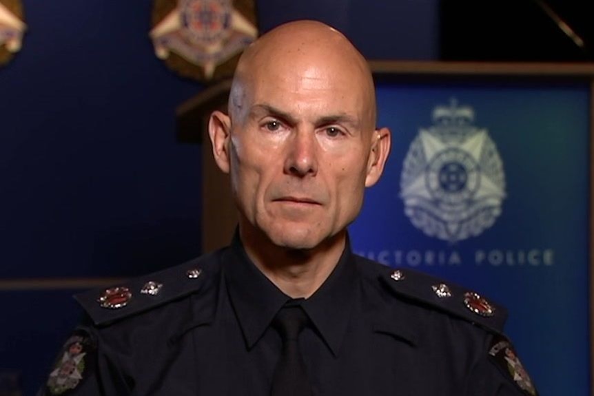 Andrew Crisp in front of a podium with a Victoria Police logo on it.