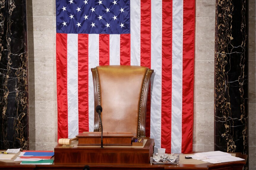 A leather chair sitting empty in front of a US flag