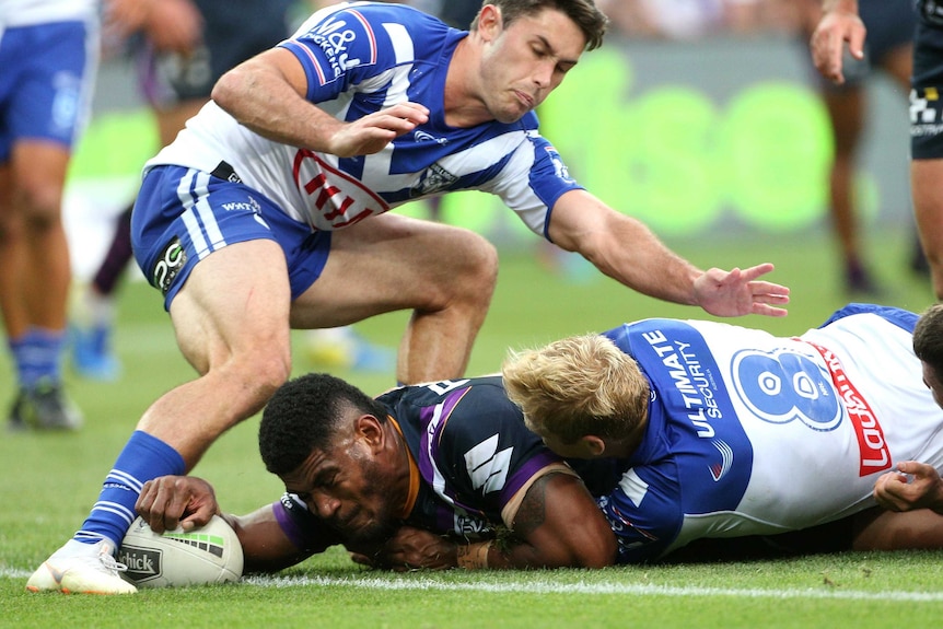 Tui Kamikamica puts the ball down for a try as he is tackled by the Bulldogs defence.
