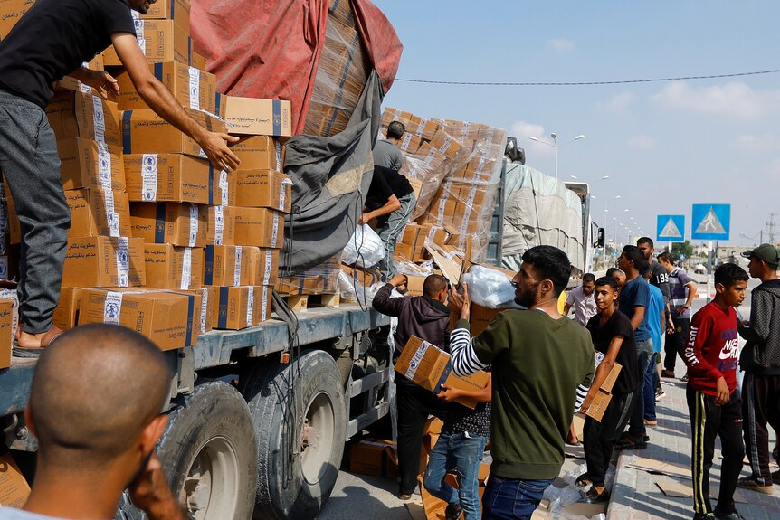 Palestinians grab boxes on trucks 