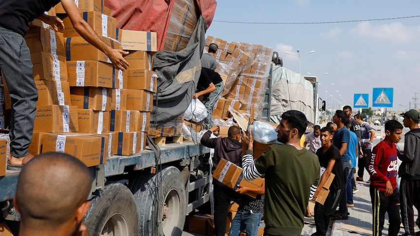 Palestinians grab boxes on trucks 