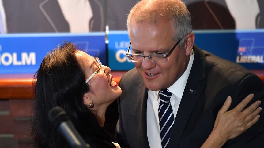 Gladys Liu rests her hand on Scott Morrison's shoulder and appears to embrace him in front of a microphone.