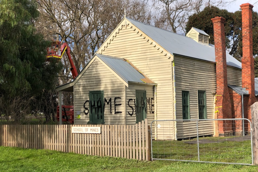 The word shame is written on a historic building in large black letters