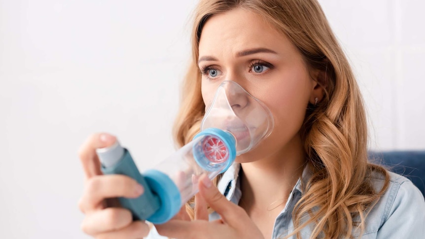 Asthmatic woman using inhaler with spacer