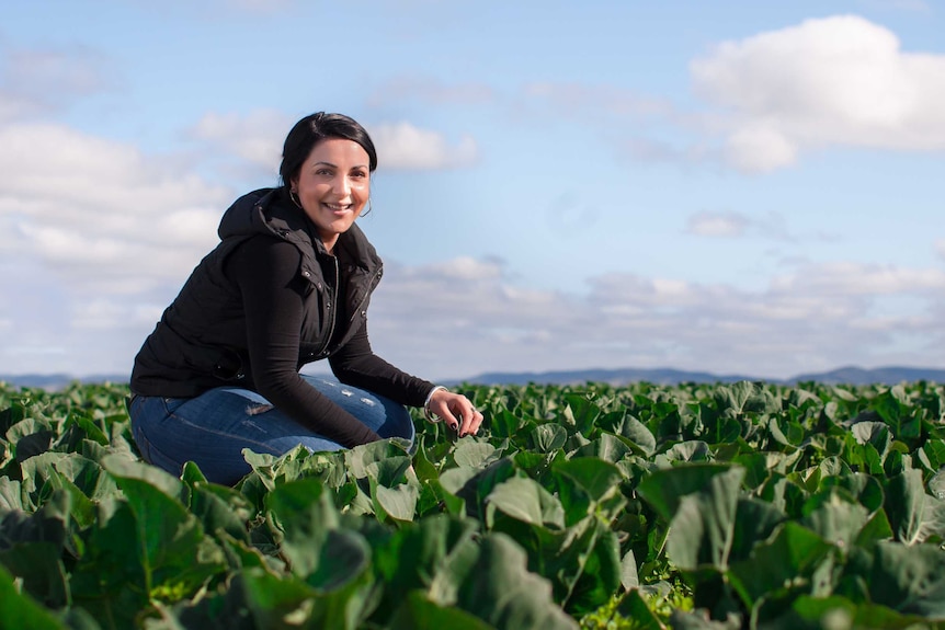 A woman squats down in a crop