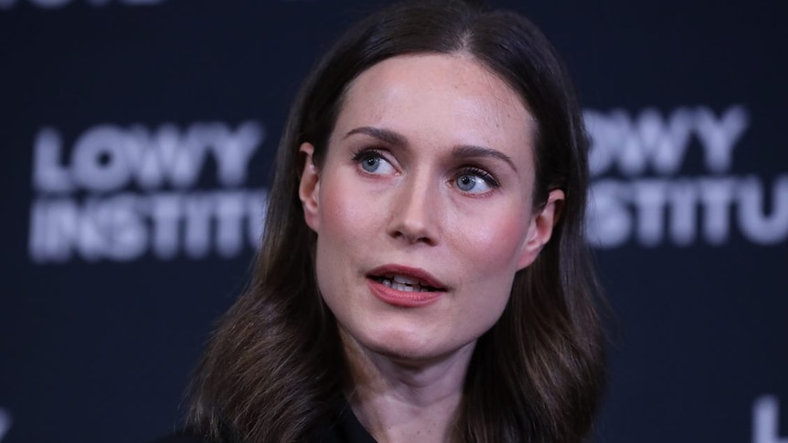 Sanna Marin wearing a black suit making an address in front of a lowy institute backdrop