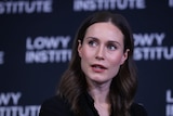 Sanna Marin wearing a black suit making an address in front of a lowy institute backdrop