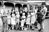 an old black and white photo of a group of children with men either side holding a very long black snake
