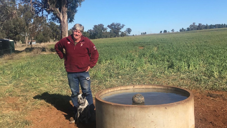 A man stands with a dog next to a water tank.