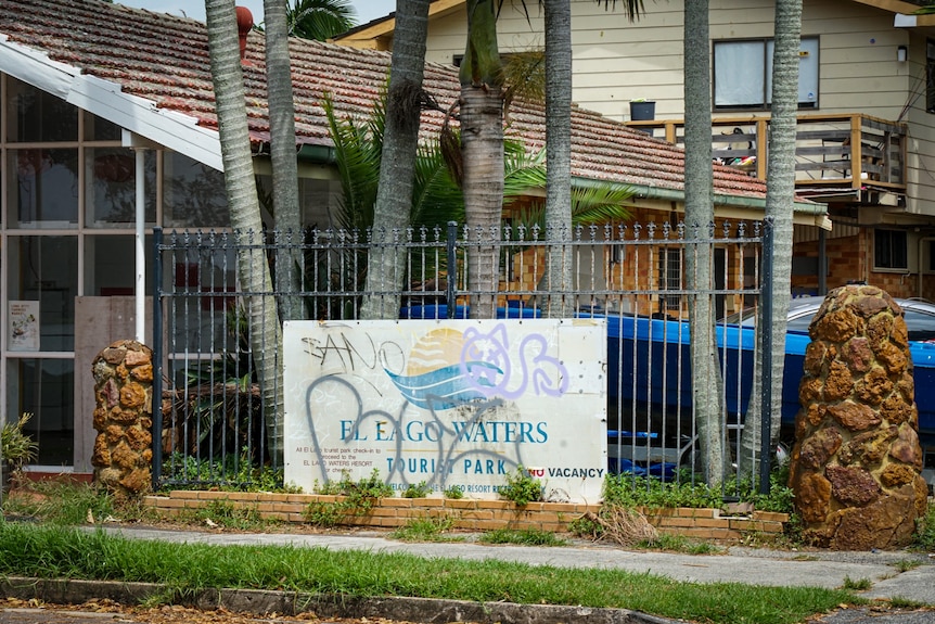 A sign for a tourist park covered in graffiti.