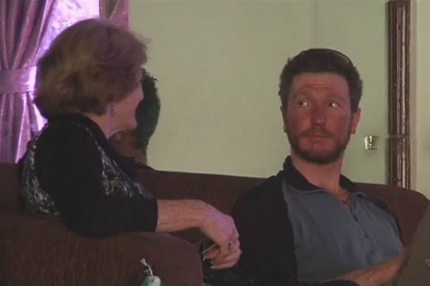 Robert Gropel sits in on a couch with his parents