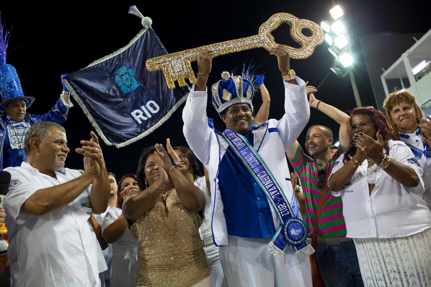 The king of this year's Carnival in Rio de Janeiro holds up a ceremonial key as onlookers applaud.