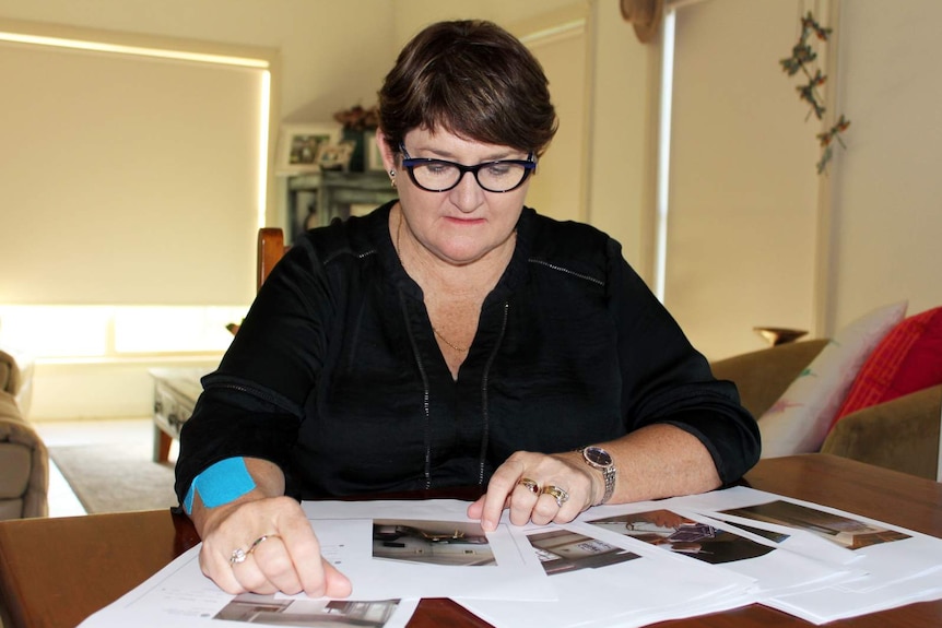 woman in glasses looking sitting down at printouts