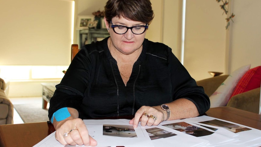 woman in glasses looking sitting down at printouts