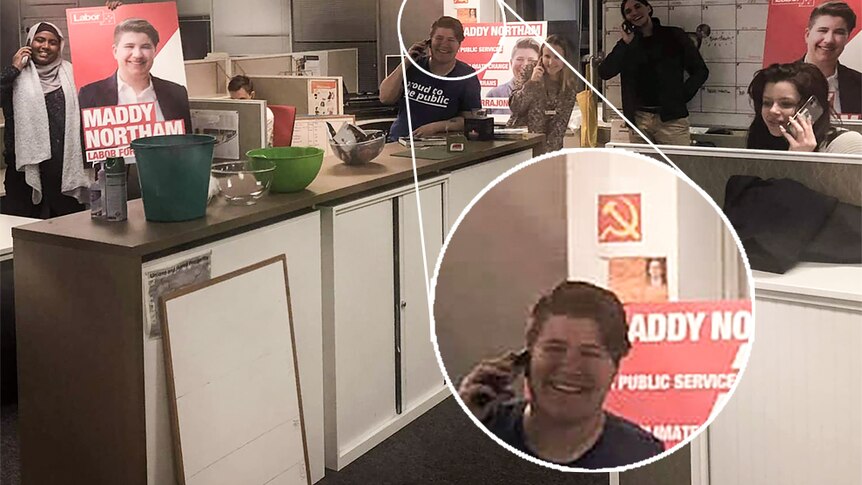 A woman in an office, with a small hammer and sickle poster on the wall.