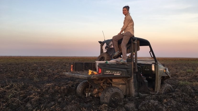 Woman sitting on top of a bogged ATV on Northern Territory floodplain at sunset