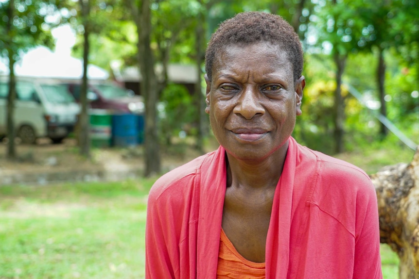 A PNG woman sitting in a garden in a red top
