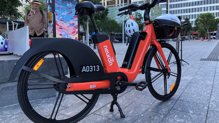 A bright orange e-bike resting on its stand in Brisbane's King George Square