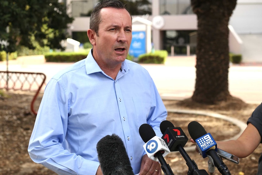 Mark McGowan stands in front of a bunch of microphones and speaks.