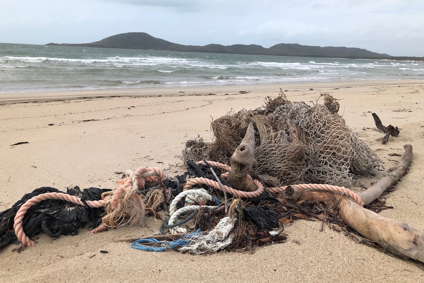Pile of marine debris and nets on beach.
