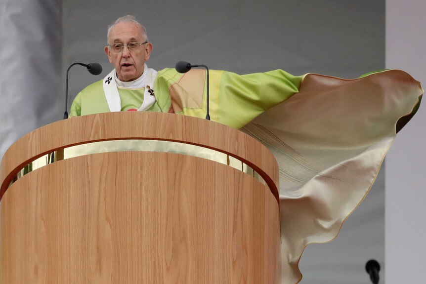 Pope Francis stands on a stage delivering mass.