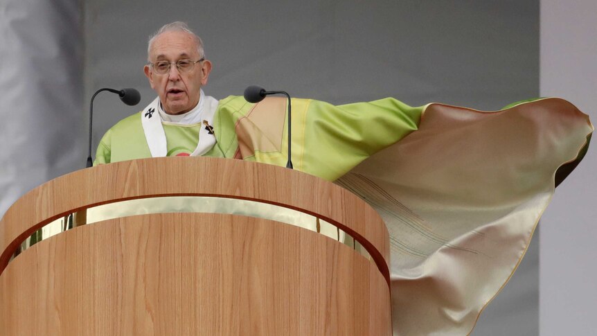 Pope Francis stands on a stage delivering mass.