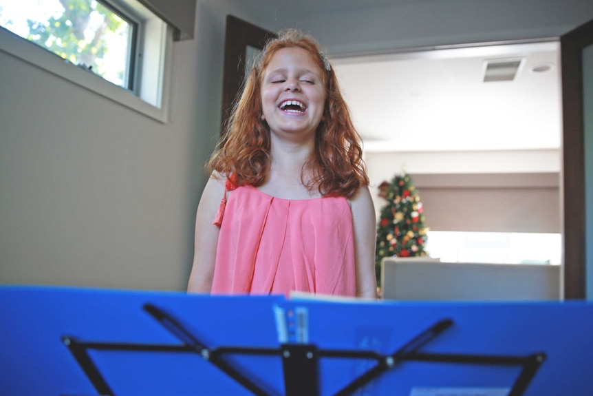 Lilly Cascun singing carols in her music room at home.
