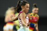 A Brisbane Lions AFLW player prepares to kick the ball during a match.