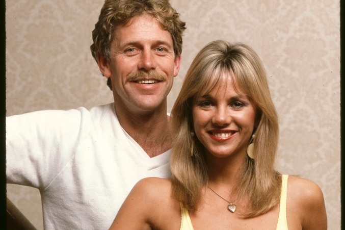 Alby Mangels and Judy Green, both three-quarter-length, mostly full face, standing at bottom of wooden staircase