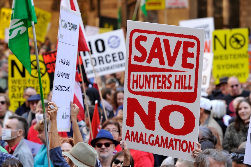 Protesters holding banners against council mergers at a protest in sydney in May 29, 2016